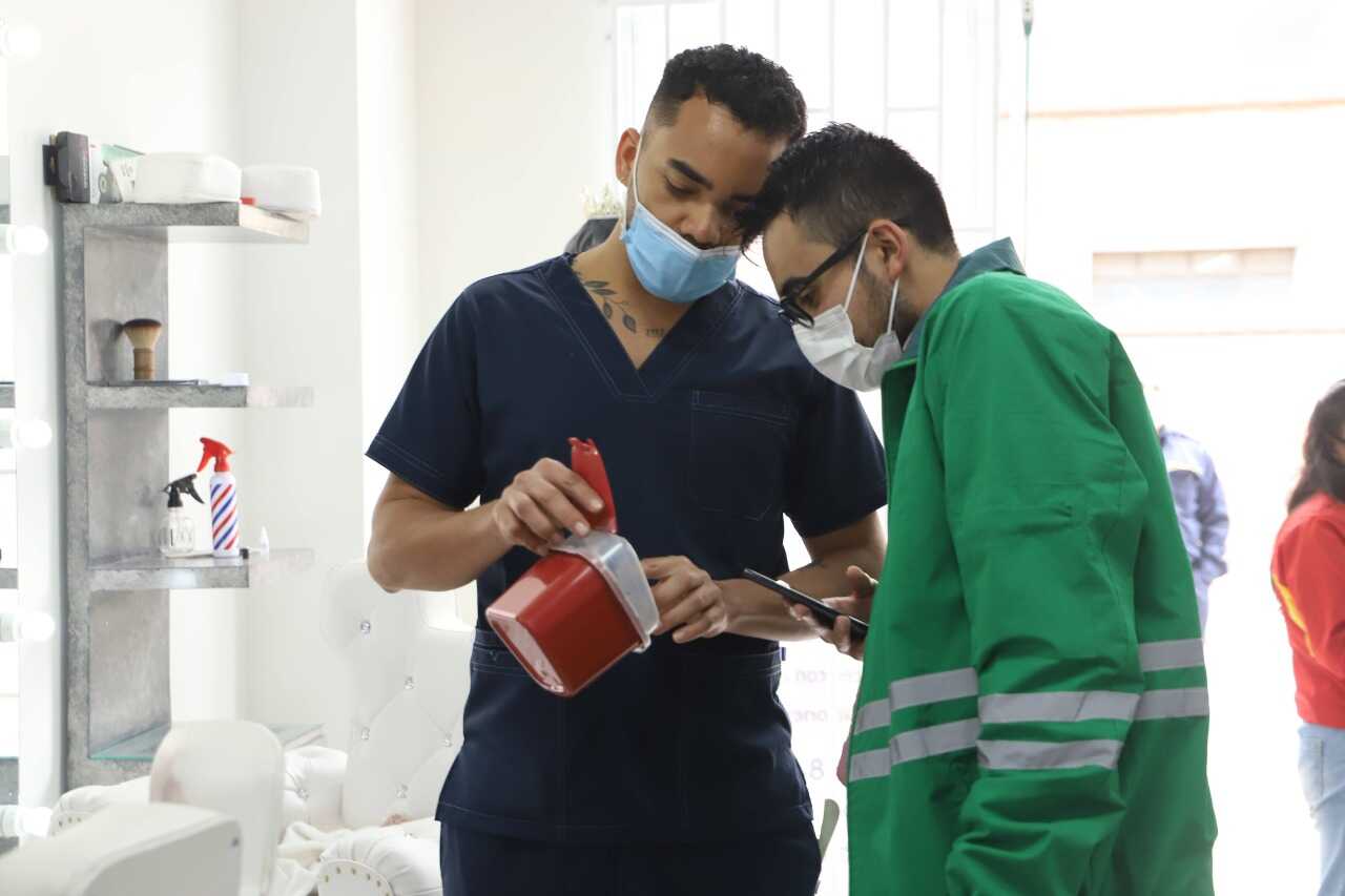 Verificación del manejo de residuos hospitalarios. Foto:Comunicaciones, Secretaría de Ambiente. Trabajador de peluquería explica a profesional de la Secretaría de Ambiente el manejo de sus residuos hospitalarios y similares.