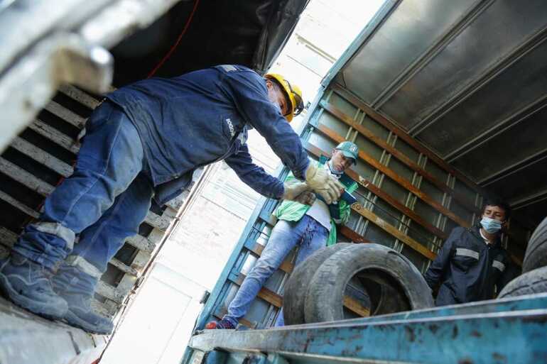 Personas ordenan llantas usadas recolectadas.