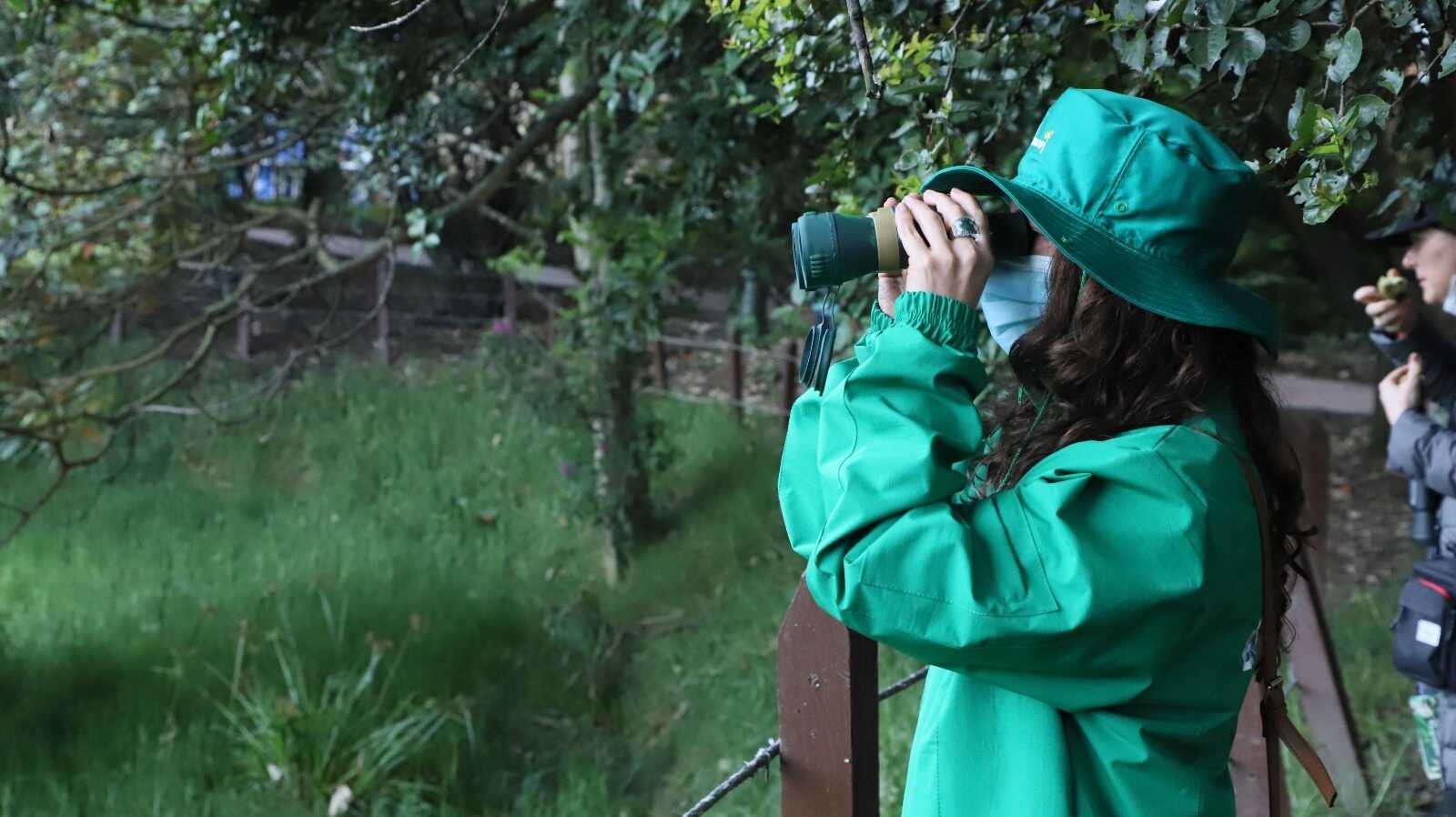 mujer observando con binoculares la biodiversidad de Bogotá